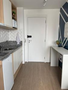 cocina con armarios blancos y puerta blanca en Flat completo com piscina, 50m do metrô Brás!, en São Paulo