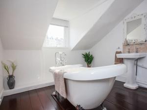 a white bathroom with a sink and a bath tub at Large House, sleeps 10 with incredible sea views in Ilfracombe