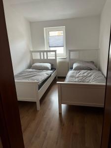 2 Betten in einem kleinen Zimmer mit Fenster in der Unterkunft FeWo Köthen 