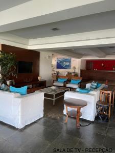 a living room with white couches and a tv at Le Corsaire in Búzios