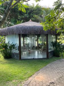a cottage with a thatched roof and a patio at Le Corsaire in Búzios