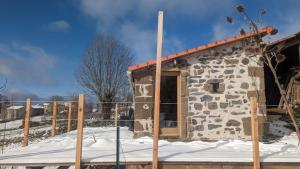 een stenen huis in de sneeuw met een hek bij Chambre d'hôtes privative Au creux du nid in Siaugues Ste Marie