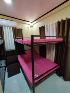 two bunk beds in a room with pink sheets at 8-pax Jumongs Transient in Bantay