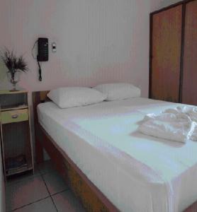 a white bed sitting in a bedroom next to a wall at Chamonville Hospedagem in Belo Horizonte