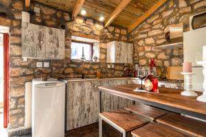 cocina con paredes de piedra y nevera blanca en Villa Nikos, en Cefalonia