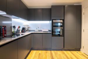 a kitchen with black cabinets and a wooden floor at Modern, Light-Filled Studio in Trendy North London in London