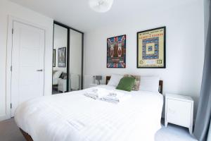 a white bedroom with a large white bed at Pass the Keys Cosy Studio flat with a Balcony in London