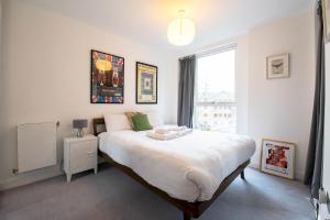 a bedroom with a large white bed with a window at Modern, Light-Filled Studio in Trendy North London in London