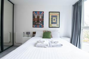 a bedroom with a large white bed with towels on it at Pass the Keys Cosy Studio flat with a Balcony in London