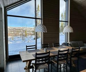 een eetkamer met een tafel en stoelen en een groot raam bij Tiltalende hytte med fin utsikt in Beitostøl