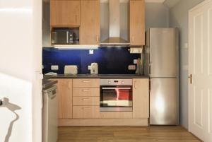 cocina con armarios de madera y nevera de acero inoxidable en Blue Sparrow House - parking, en Portsmouth