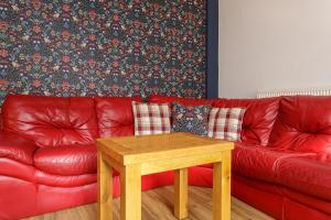 a red couch with a wooden table in a living room at Blue Sparrow House - parking in Portsmouth