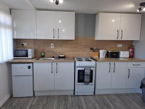 a kitchen with white cabinets and a stove top oven at Sandhaven Beach Chalets in South Shields