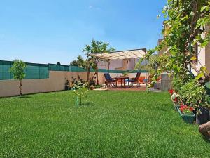 a backyard with a grass yard with a table and a pergola at Apartments Zadro in Tribunj