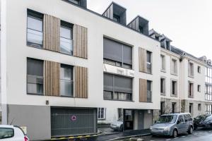 einen Blick nach außen auf ein weißes Gebäude mit schwarzen Fenstern in der Unterkunft Kereon in Quimper