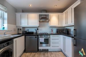 a kitchen with white cabinets and stainless steel appliances at Thornaby House TSAC in Thornaby on Tees