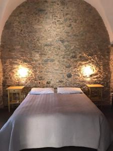 a bed in a room with a stone wall at Ca Du Ventu in Carbuta