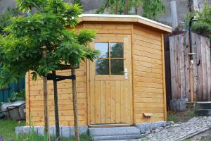 ein Holzschuppen mit einer Tür neben einem Zaun in der Unterkunft Ferienhof Gräfe - 3-Seiten Hof mit großem Garten, Pool & Sauna in Meißen