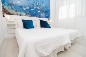 een witte slaapkamer met een groot bed met blauwe kussens bij Marinero in La Restinga