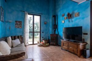 Sala de estar azul con sofá y TV en Villa Cavalieri in Vedriano, en Roncovetro