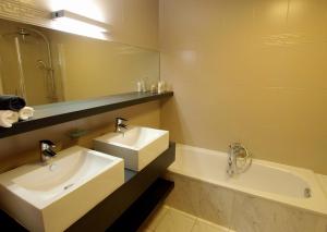 ein Badezimmer mit zwei Waschbecken, einer Badewanne und einem Spiegel in der Unterkunft Private House in Blankenberge