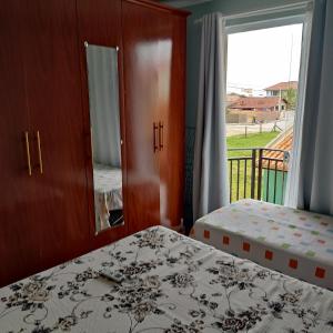 una camera da letto con due letti e una grande finestra di Apartamento 103 Praia do Ervino - SFS a São Francisco do Sul