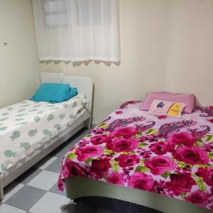 una camera con due letti singoli e fiori rosa di Apartamento 103 Praia do Ervino - SFS a São Francisco do Sul