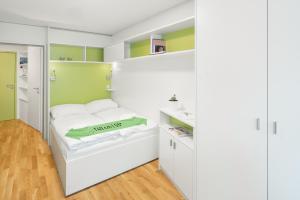 myNext - Hotel Leo في فيينا: غرفة نوم بسرير ابيض وجدران خضراء