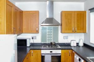 a kitchen with wooden cabinets and a stove top oven at Allen Wednesbury Accommodation in Darlaston
