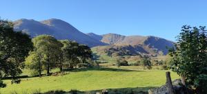 a green field with mountains in the background at Shackleton Rooftop Tent Rental from ElectricExplorers in Hawkshead