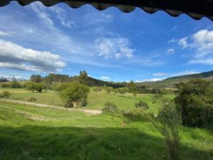 a field of grass with a road in the distance at Suanoga - Finca Turística in Pesca