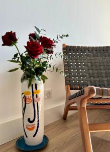 a vase with roses in it sitting next to a chair at Nouveau ! T2 neuf avec vue imprenable mer in Ajaccio