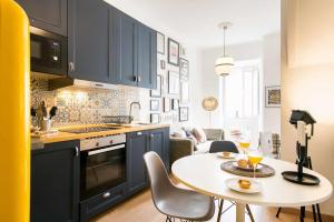 a kitchen with a table with chairs and a kitchen with blue cabinets at St Amaro- Chic Terrace Studio Lisbon Congress in Lisbon