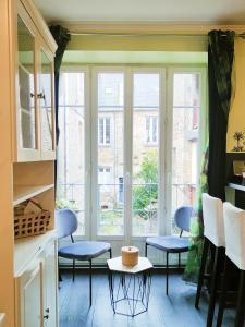 a kitchen with blue chairs and a large window at STUDIO DE L'HORLOGE in Dinan