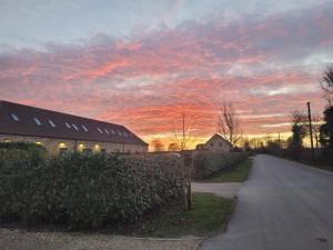 a road leading to a building with a sunset in the background at Field Maple Barn, Ashlin Farm Barns in Lincoln