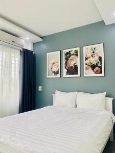 - une chambre dotée d'un lit blanc avec 4 photos sur le mur dans l'établissement Hotel Mini, à Phú Thọ