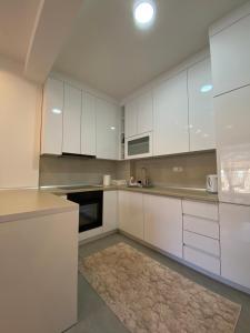 a white kitchen with white cabinets and a rug at Apartman EN in Trebinje