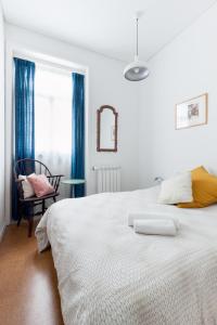 ein weißes Schlafzimmer mit einem großen weißen Bett und einem Stuhl in der Unterkunft Apartamento na Vila in Fão