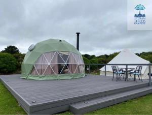a tent and a table and chairs on a deck at Glamping Dome Elysian Fields in Helston
