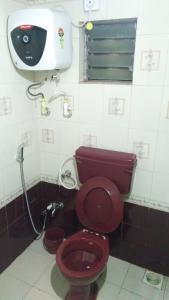 een badkamer met een rood toilet en een wastafel bij Krishna Niwas in Mahabaleshwar