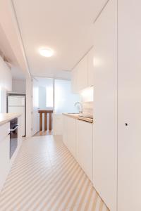 eine Küche mit weißen Schränken und Holzböden in der Unterkunft Apartamento na Vila in Fão