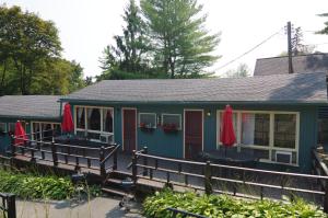 a green cottage with red doors and a deck at Cramers Point Lake Breeze in Lake George