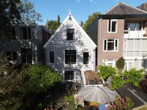 アムステルダムにあるKlavergelukの傘を前に置いた白い家