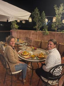 a man and woman sitting at a table with food at DAR TAWJA in Asguine