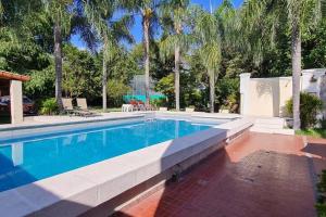 a swimming pool in a yard with palm trees at Casa quinta en la ruta 1 km 3.5 in Santa Fe