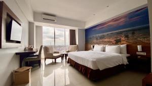 ein Hotelzimmer mit einem Bett, einem Tisch und Stühlen in der Unterkunft Ascent Premiere Hotel and Convention in Malang