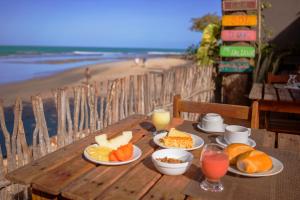 una mesa de madera con platos de comida y una playa en Pousada Ponta Da Pedra, en Jericoacoara