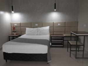 ein Schlafzimmer mit einem großen Bett, einem Tisch und einem Schreibtisch in der Unterkunft Hotel Samambaia in Indiara 