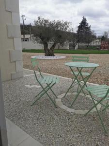 シャンプニエにあるAngoulême Nord location Chambre indépendanteの緑の椅子2脚、テーブル1台、木