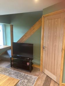 a living room with a tv and a wooden door at Whiteside Granary in Haltwhistle